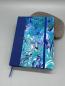 Preview: Notizbuch 17×12 cm Marmoriert – Vorderdeckel mit selbst marmoriertem Einband in Blau-Swirl, farblich passender Leinenrücken und Gummiband
