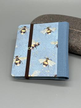 Preview: Haftnotizblock mit Stift Bienen – Rückseite mit hellblauem Leinenrücken und Metall-Eyelet, Gummiband geschlossen