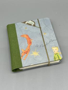 Haftnotizblock mit Stift Kleiner Prinz – Vorderdeckel mit Le Petit Prince-Illustrationen und Goldpulver-Druck von Kartos, olivgrüner Leinenrücken und Gummiband