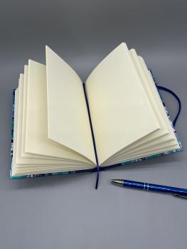 Preview: Notizbuch 17×12 cm Marmoriert – geöffnetes Buch mit altweißen Blankoseiten und Lesebändchen