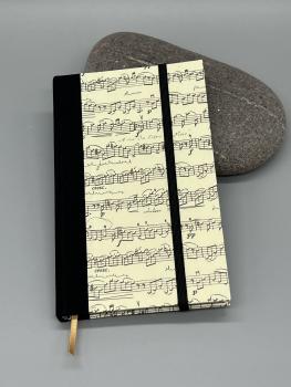 Notizbuch 9×15 cm Partitur – Vorderdeckel mit Notenmotiv und Goldpulverdruck von Kartos, schwarzer Leinenrücken, Gummiband