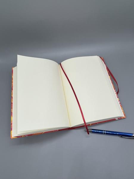 Notizbuch A5 Marmoriert – geöffnetes Buch mit altweißen Blankoseiten, Lesebändchen und Stift